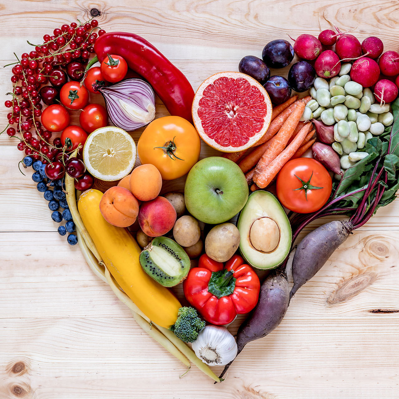 Modern composition of fresh healthy vegetables and fruits in heart shape on the wooden table in the kitchen. Healthy detox and balance diet. Lifestyle. Vegetarian vegan background. Zero waste. Top view.